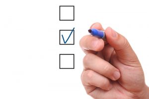 List of check boxes and hand with pen on white background